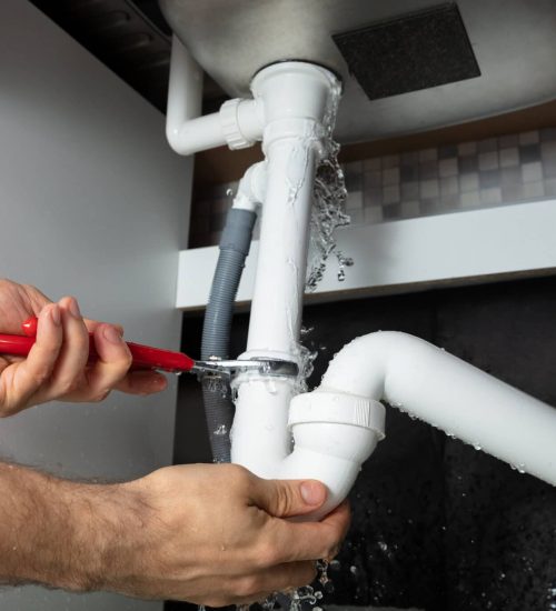 Plumber Fixing Sink Pipe With Adjustable Wrench